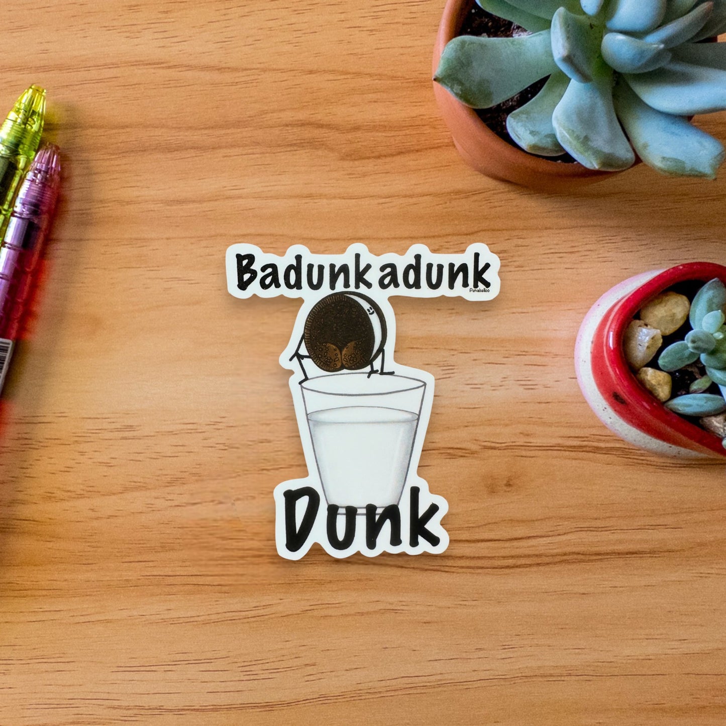 Badunkadunk Dunk cookie sticker — hand-drawn milk & cookies food pun design by Punaballoo, waterproof vinyl decal for snack lovers and humor fans.