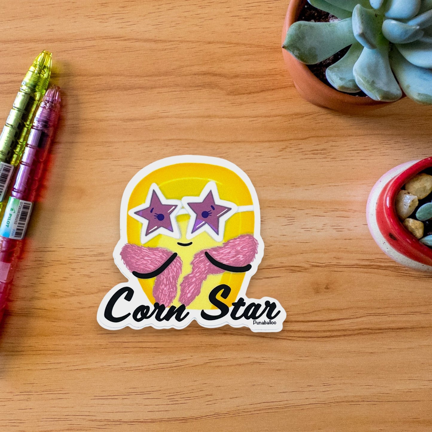 “Corn Star” corn sticker — hand-drawn food pun design by Punaballoo, waterproof vinyl decal for snack lovers and humor fans.