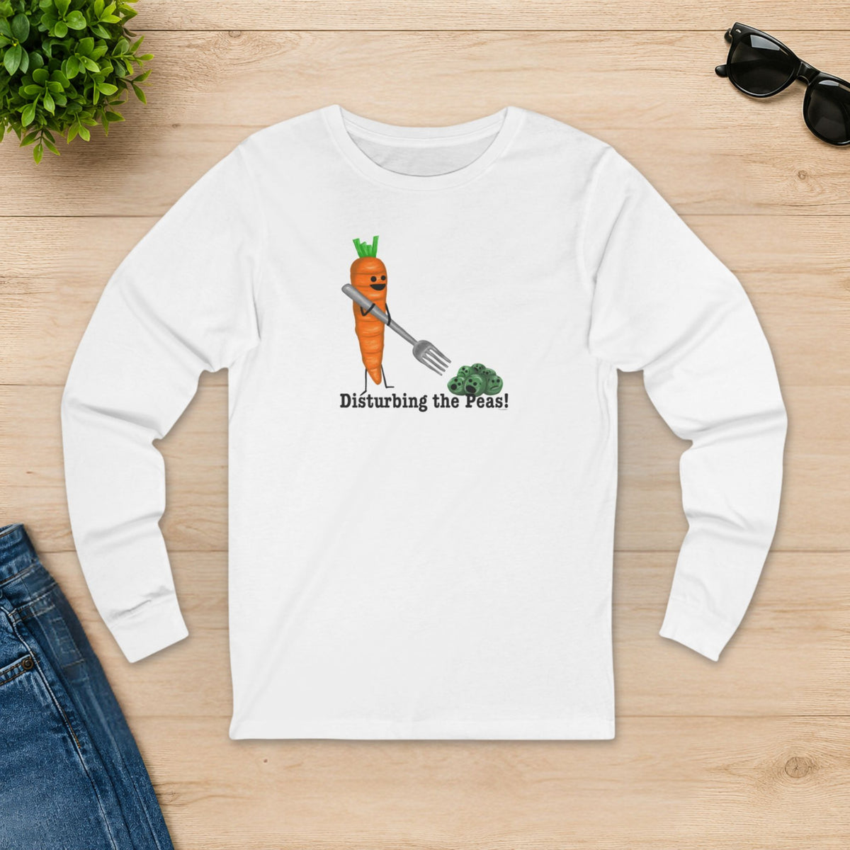 White Disturbing the Peas long sleeve shirt laid flat on a wooden table