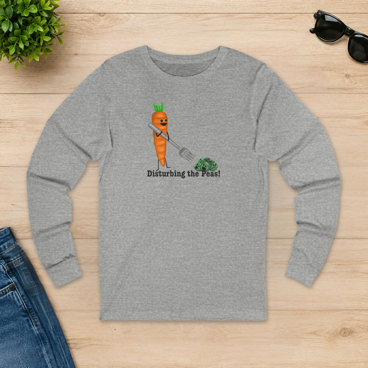 Athletic heather Disturbing the Peas long sleeve shirt laid flat on a wooden table