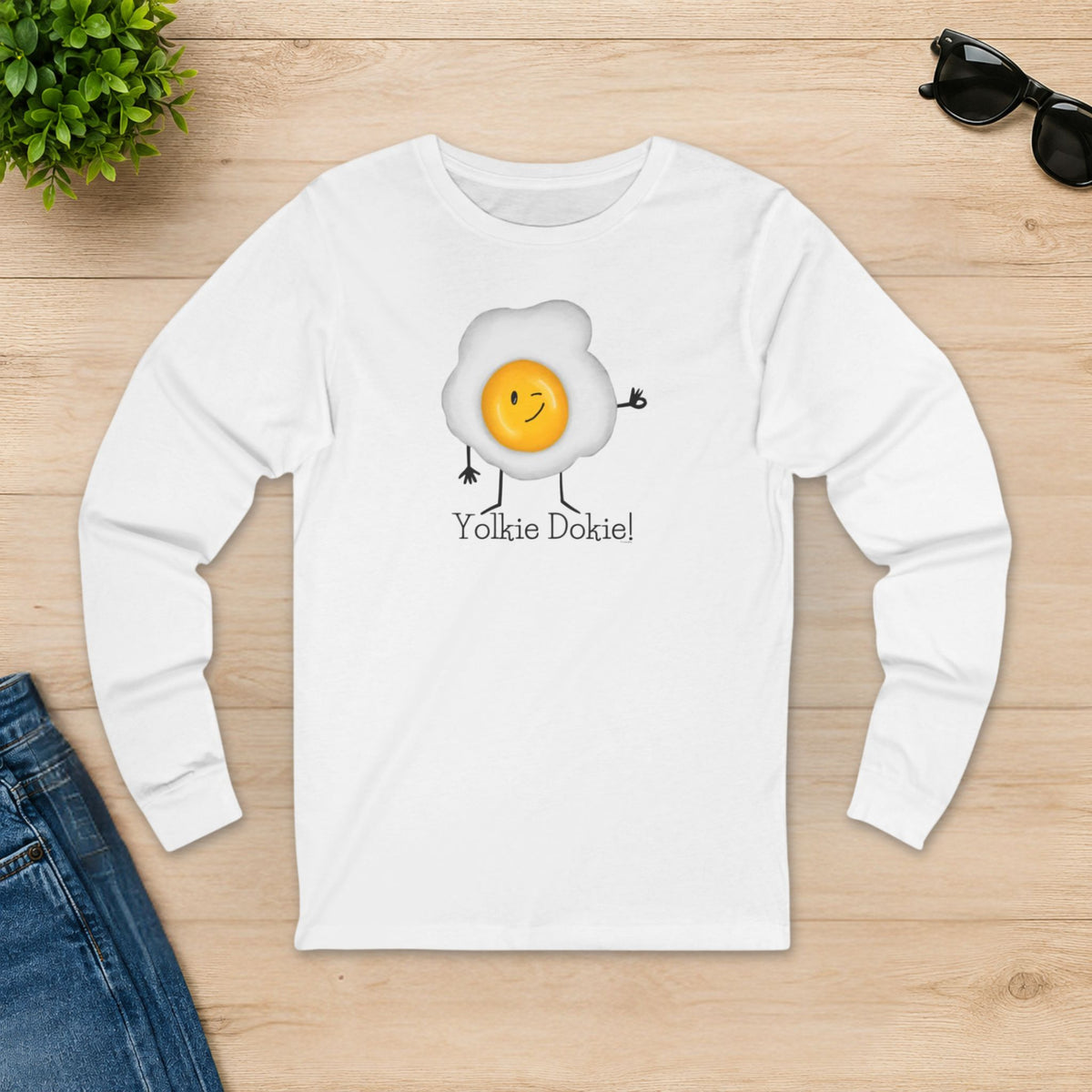 White Yolkie Dokie egg long sleeve shirt laid flat on a wooden table