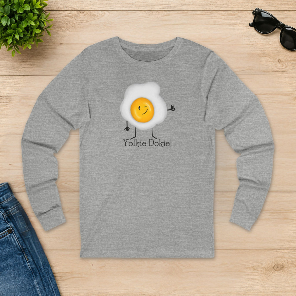 Athletic heather Yolkie Dokie egg long sleeve shirt laid flat on a wooden table