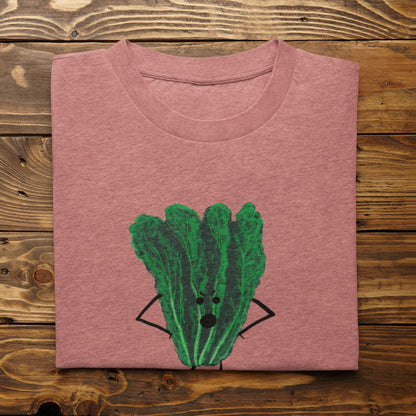 A folded light heather mauve t-shirt with Oh Kale No pun printed on the front, displayed flat on a rustic wooden plank background.