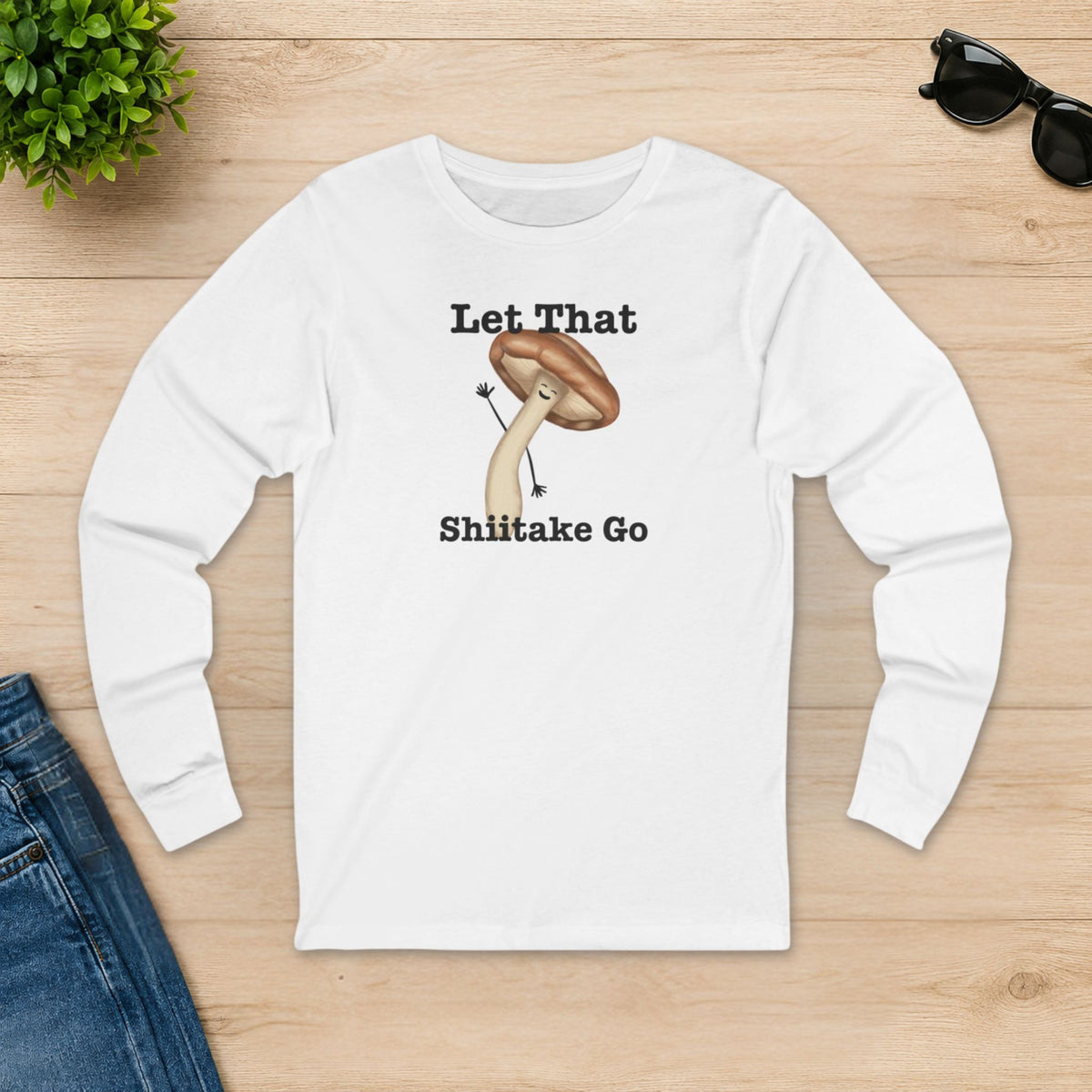 White Let That Shiitake Go long sleeve shirt laid flat on a wooden table