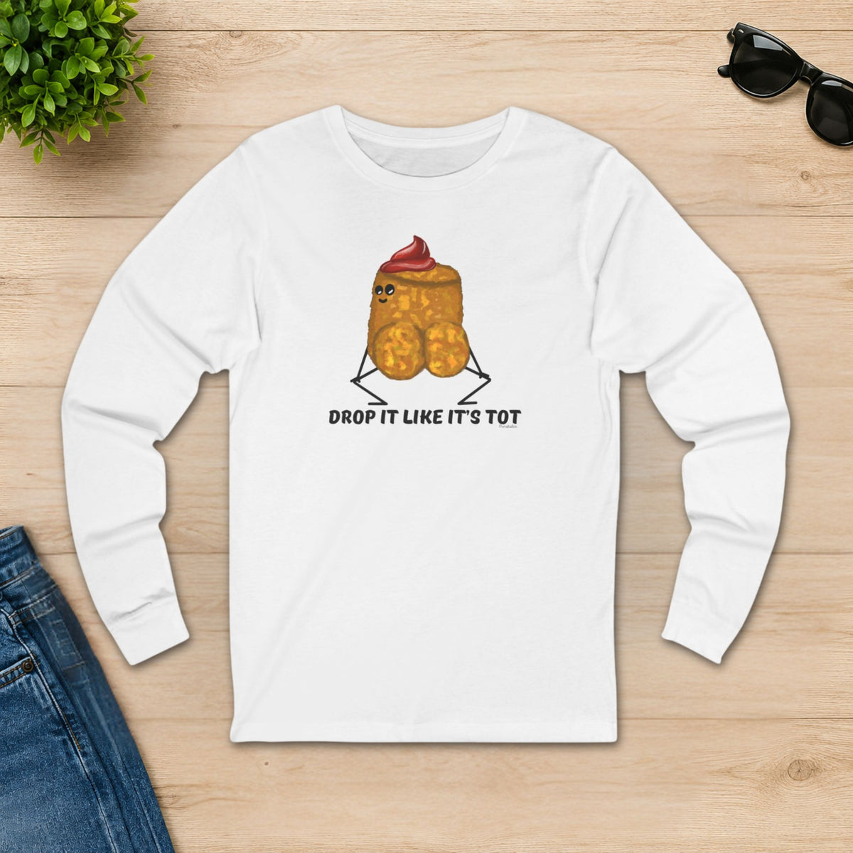 White Drop It Like It’s Tot tater tot shirt styled on a wooden tabletop