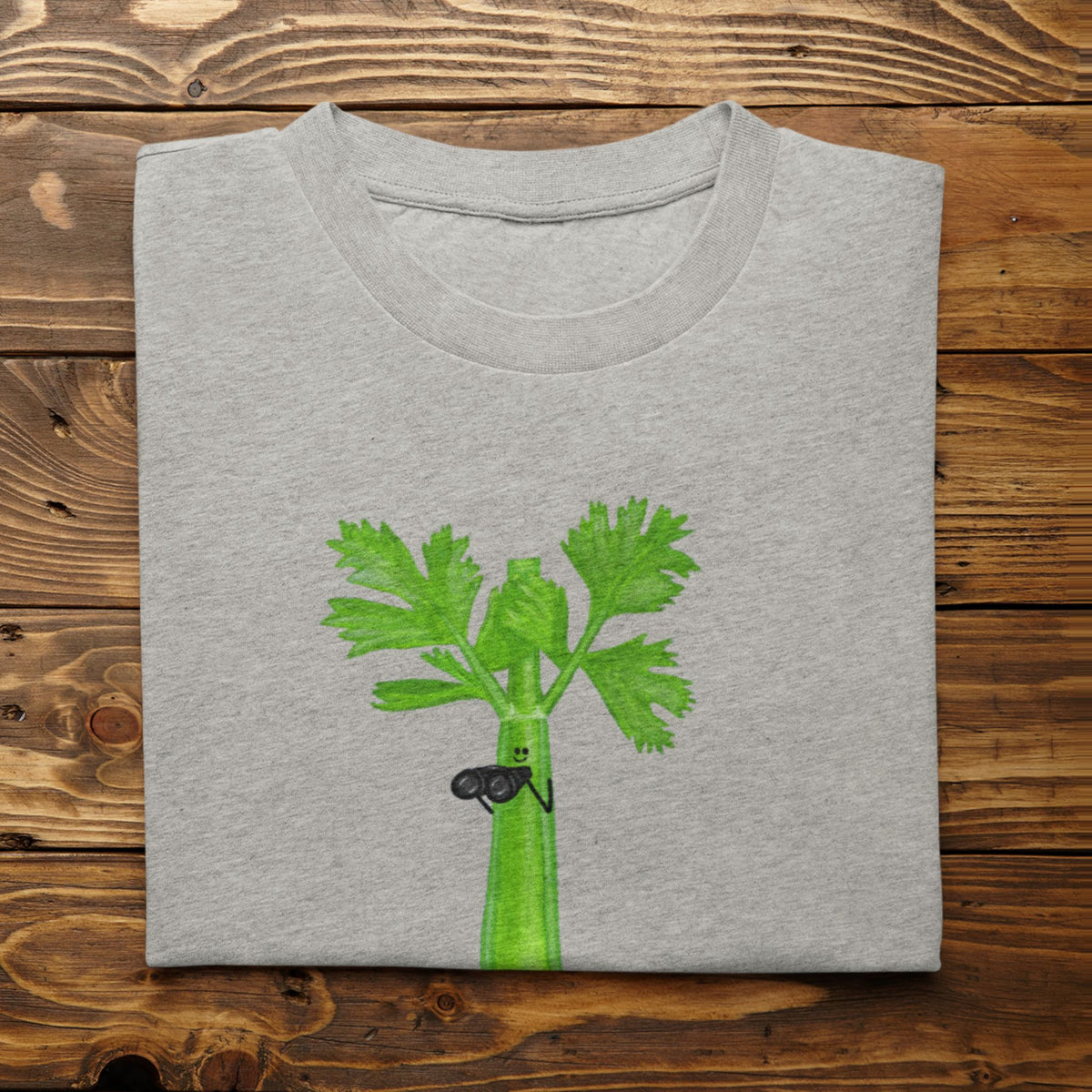 Athletic heather Stalker celery pun T-shirt flat lay featuring a green celery character holding binoculars.