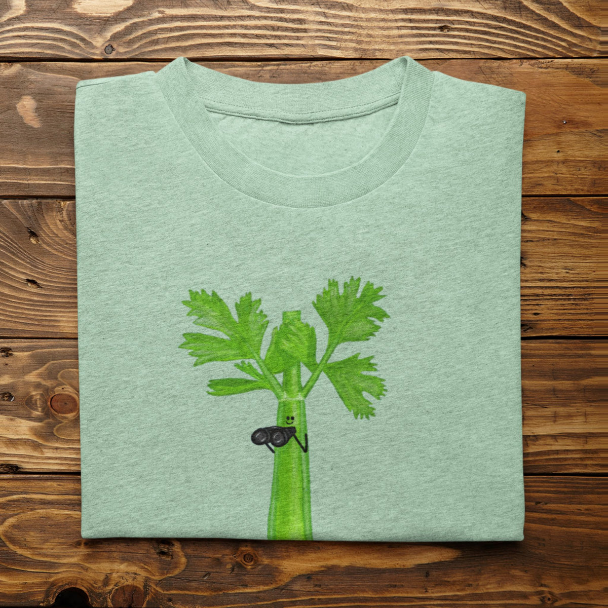 Heather mint Stalker celery pun T-shirt flat lay featuring a green celery character holding binoculars.