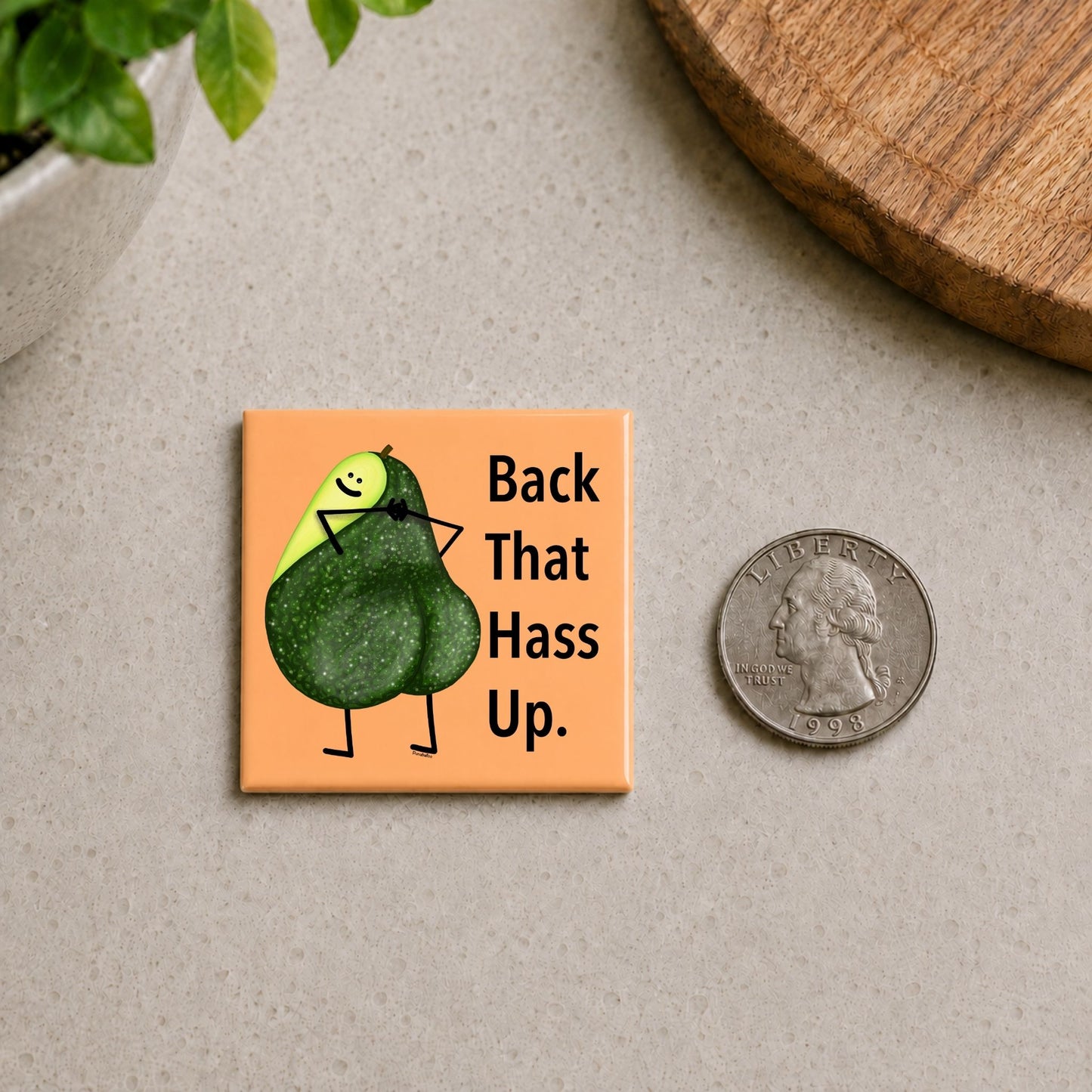 Back That Hass Up avocado pun magnet on a countertop beside a quarter for size