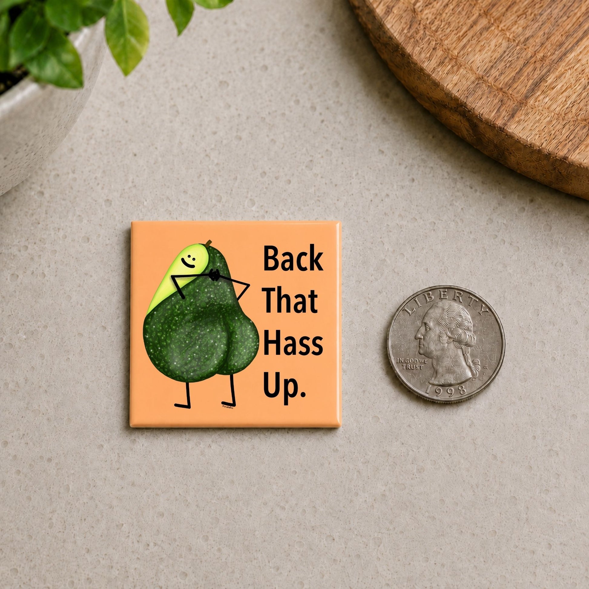 Back That Hass Up avocado pun magnet on a countertop beside a quarter for size
