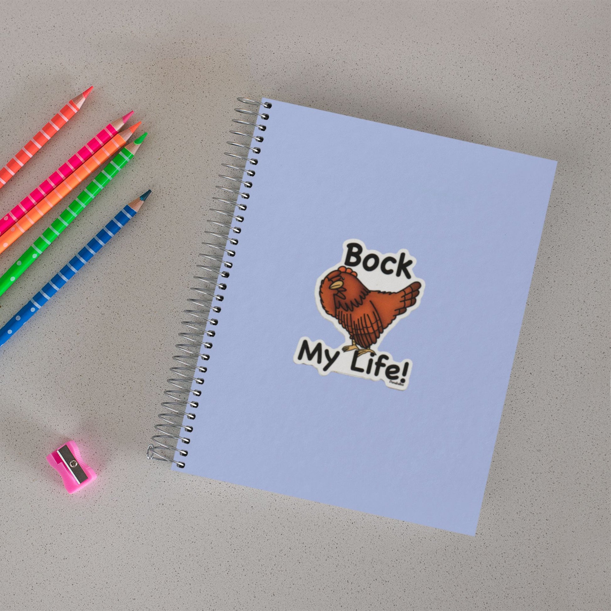 Bock My Life chicken sticker on a notebook beside colored pencils