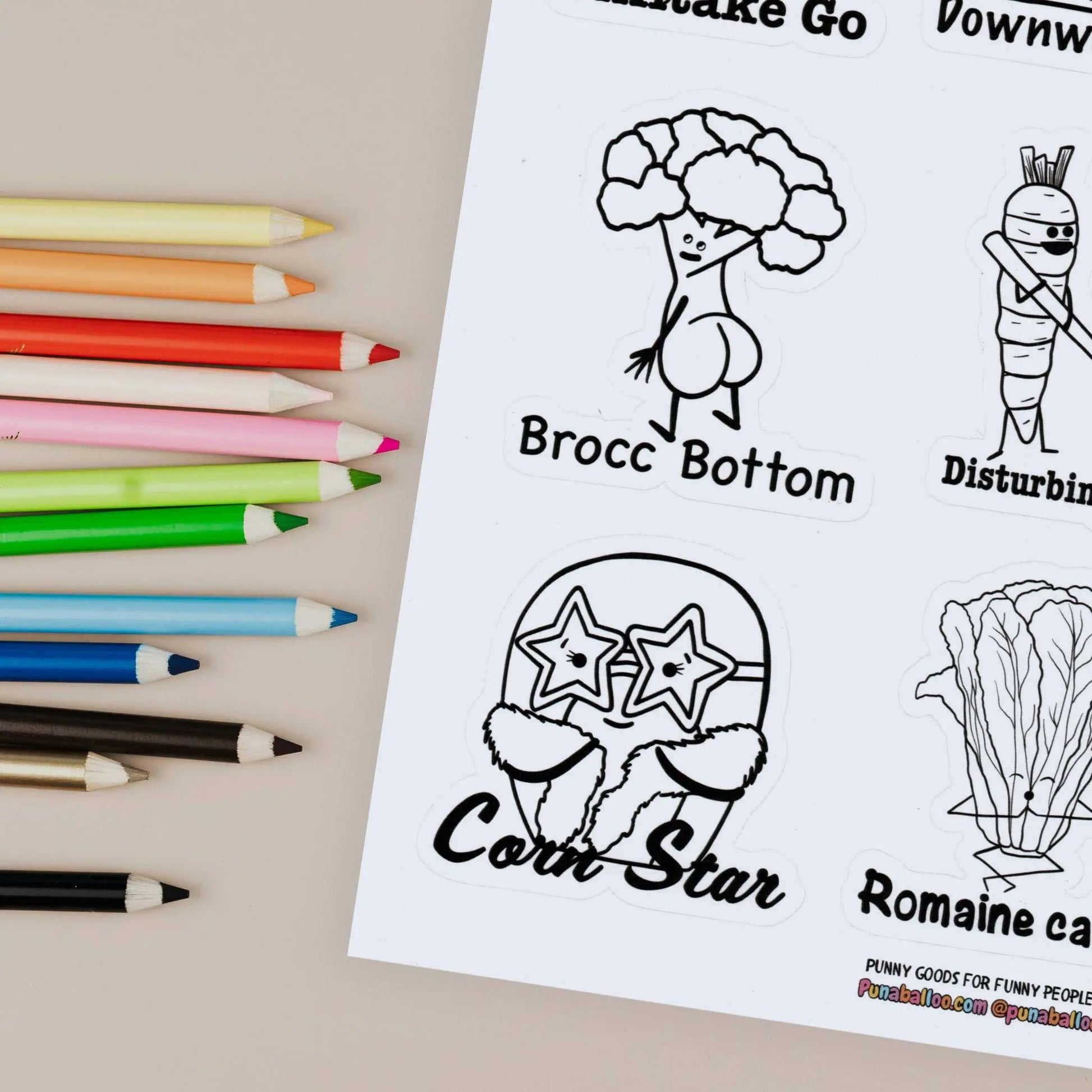 Close up Color-your-own funny food pun sticker sheet with pencils on beige background