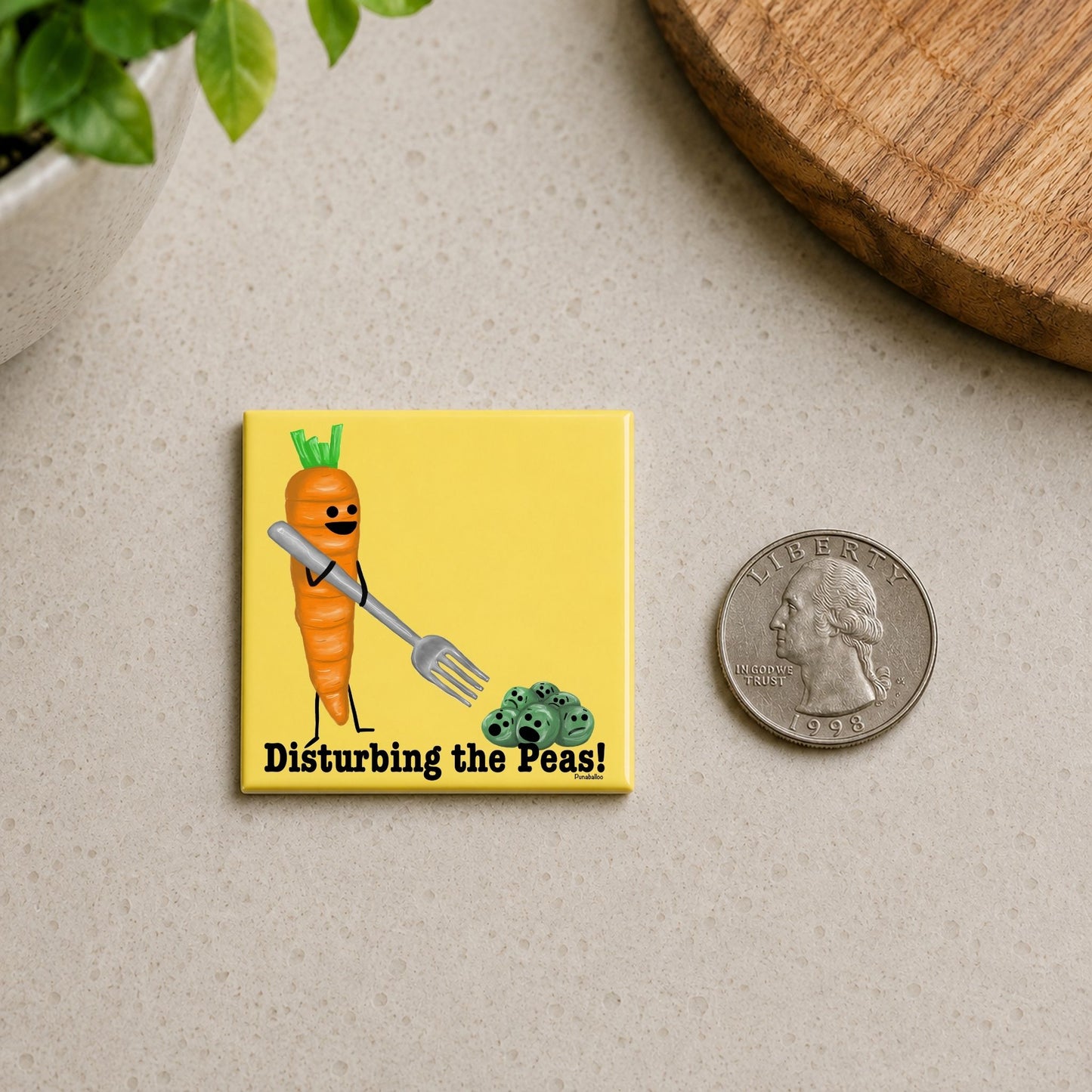 Disturbing the Peas funny carrot magnet on a countertop beside a quarter for size
