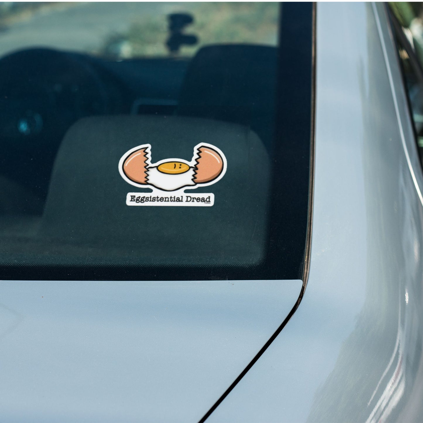 Eggsistential Dread breakfast pun sticker on a car window