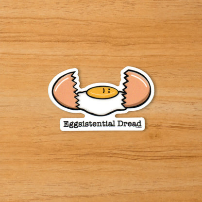 Eggsistential Dread dark humor egg sticker on a wood surface