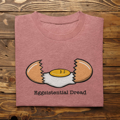 Folded heather mauve Eggsistential Dread egg pun t-shirt on rustic wood background