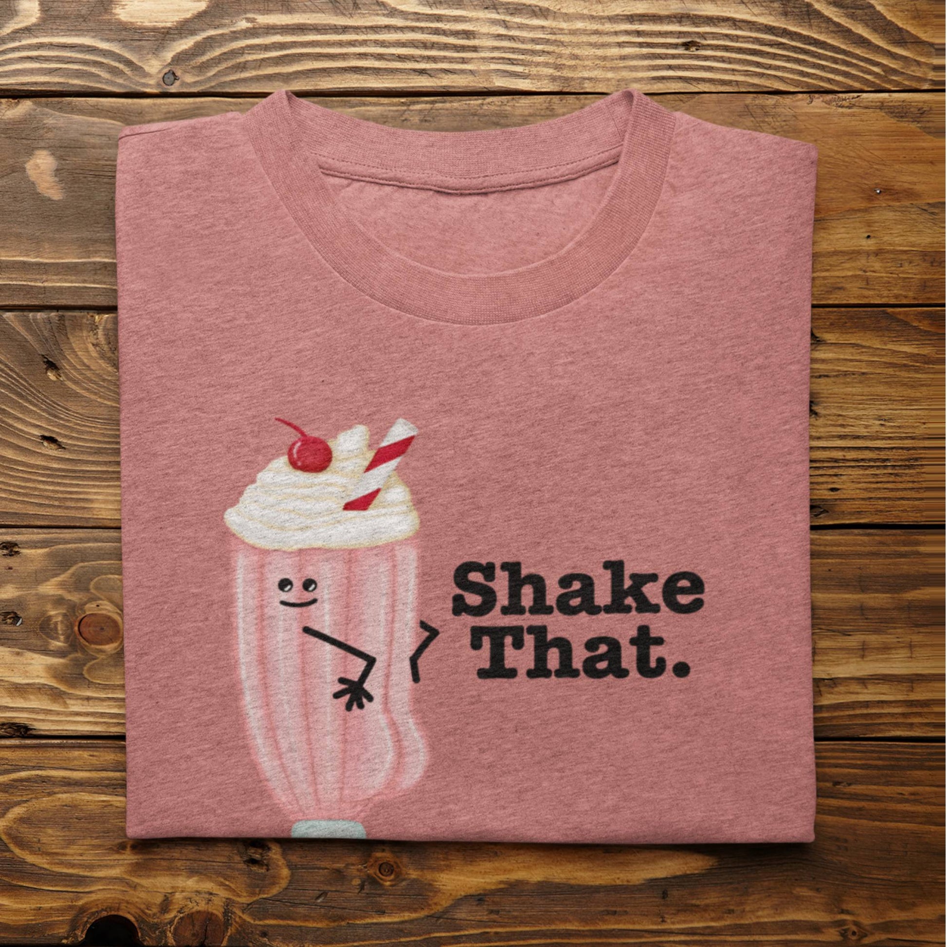 Folded heather mauve Shake That funny milkshake shirt on rustic wood background