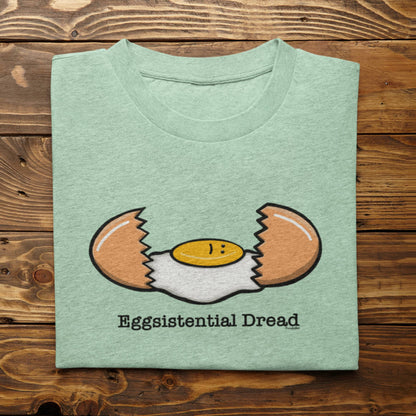 Folded heather mint Eggsistential Dread breakfast pun shirt on rustic wood background