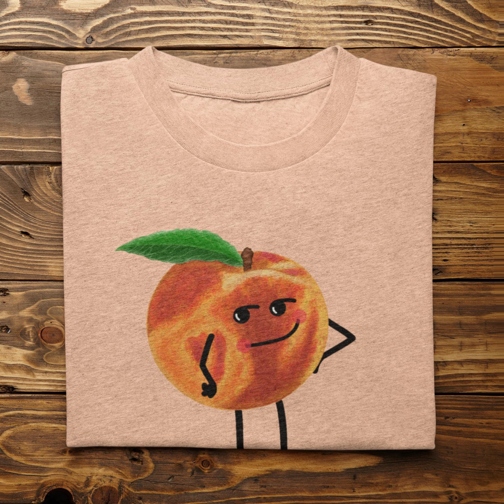 Folded heather peach Karma Is a Peach funny peach shirt on rustic wood background