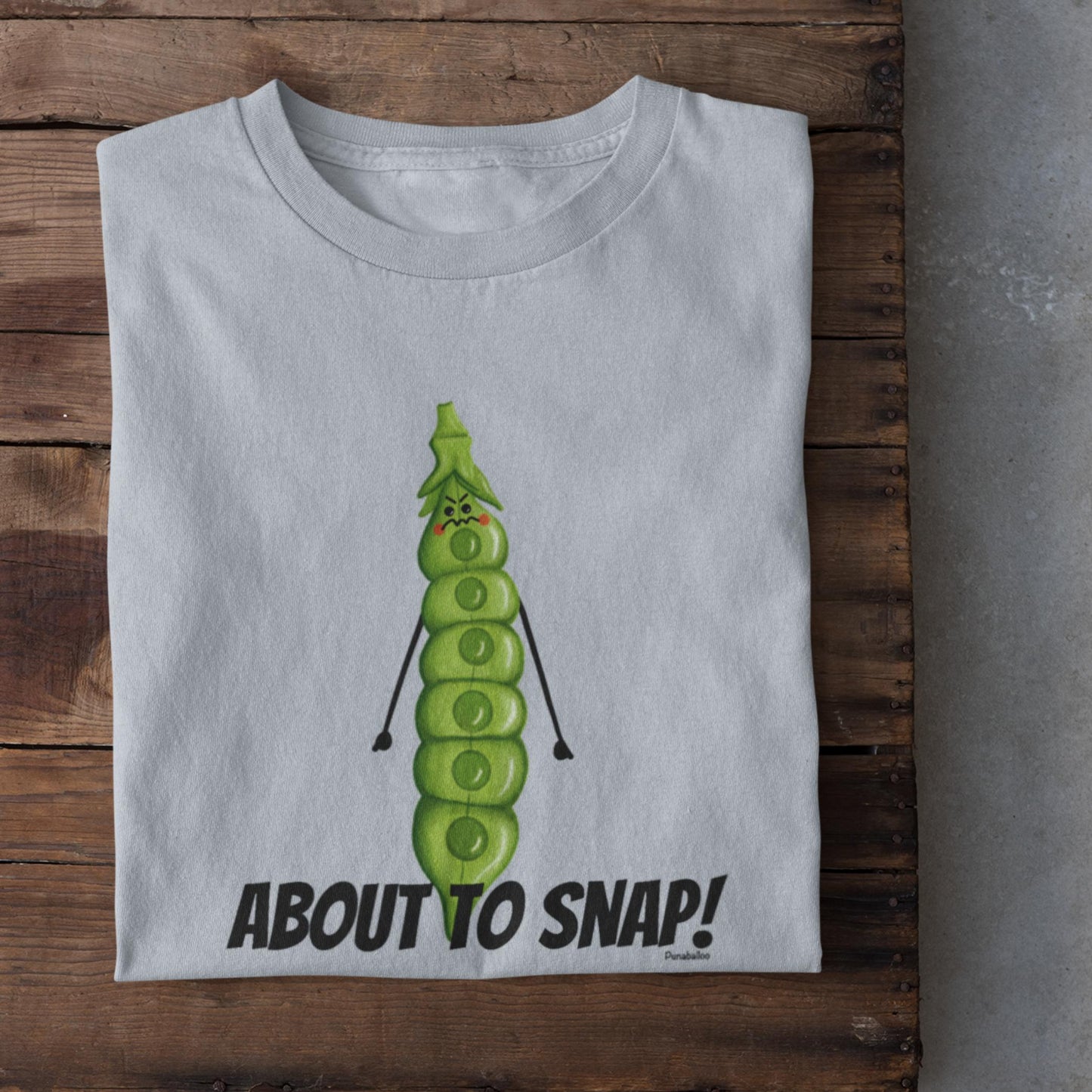 Folded light blue I’m About to Snap pea pun t-shirt on rustic wood background