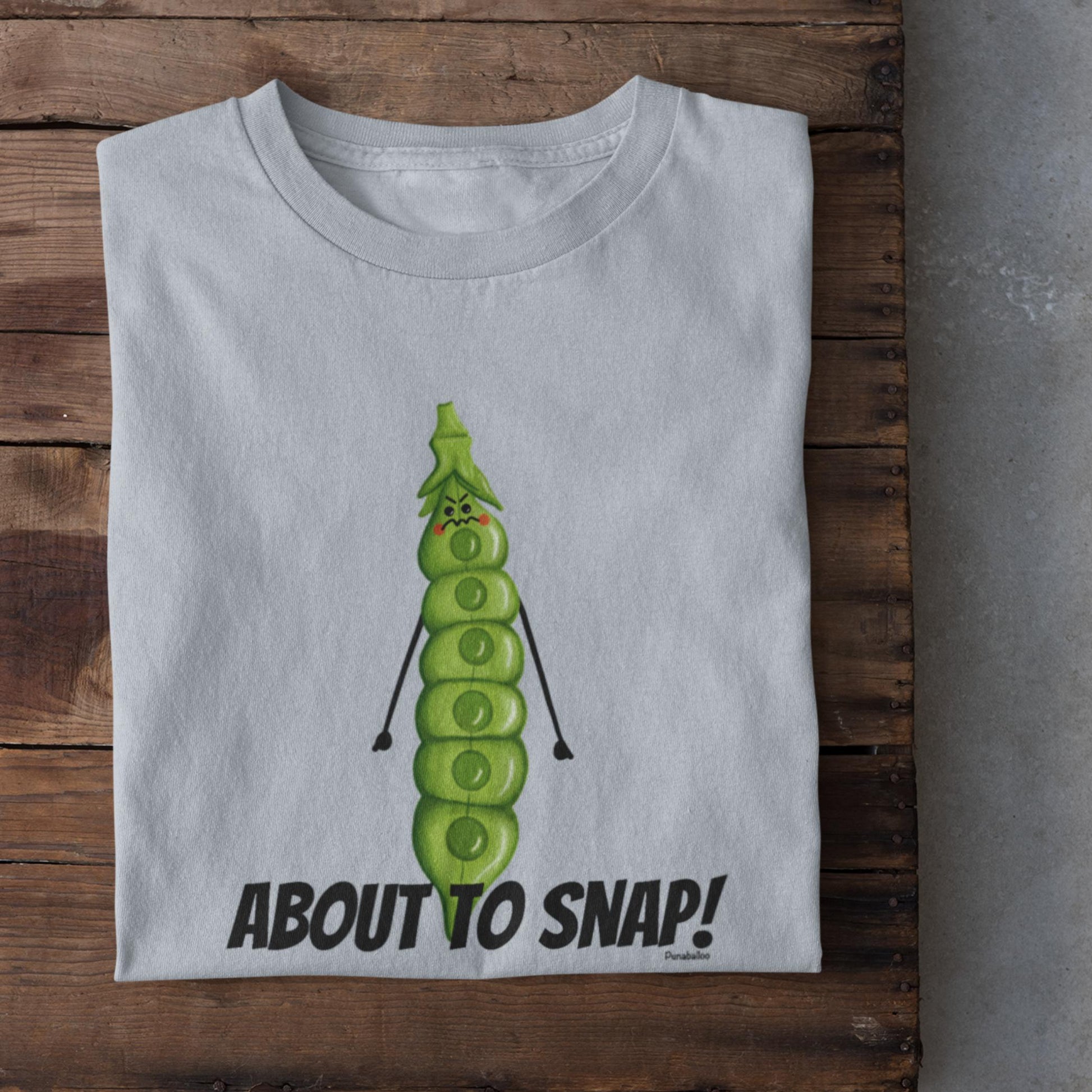 Folded light blue I’m About to Snap pea pun t-shirt on rustic wood background