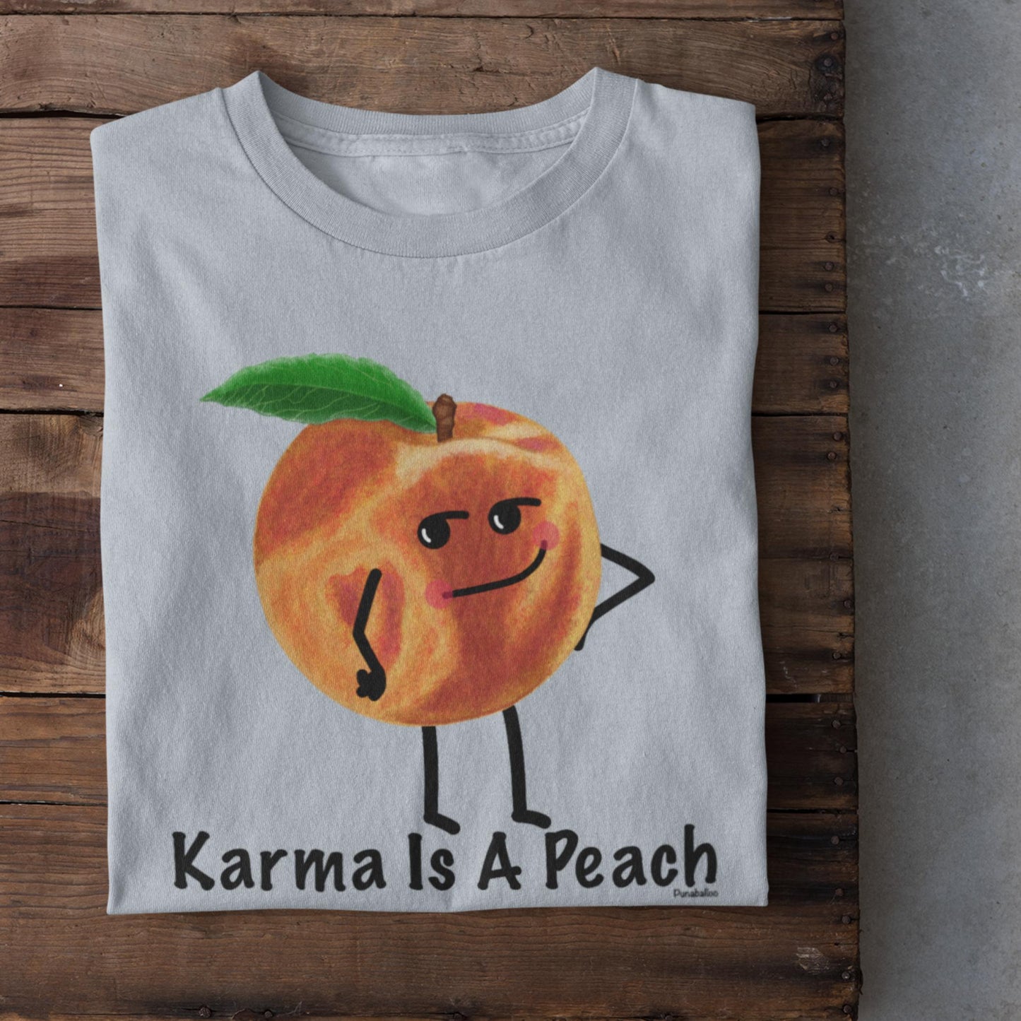 Folded light blue Karma Is a Peach funny karma t-shirt on rustic wood background