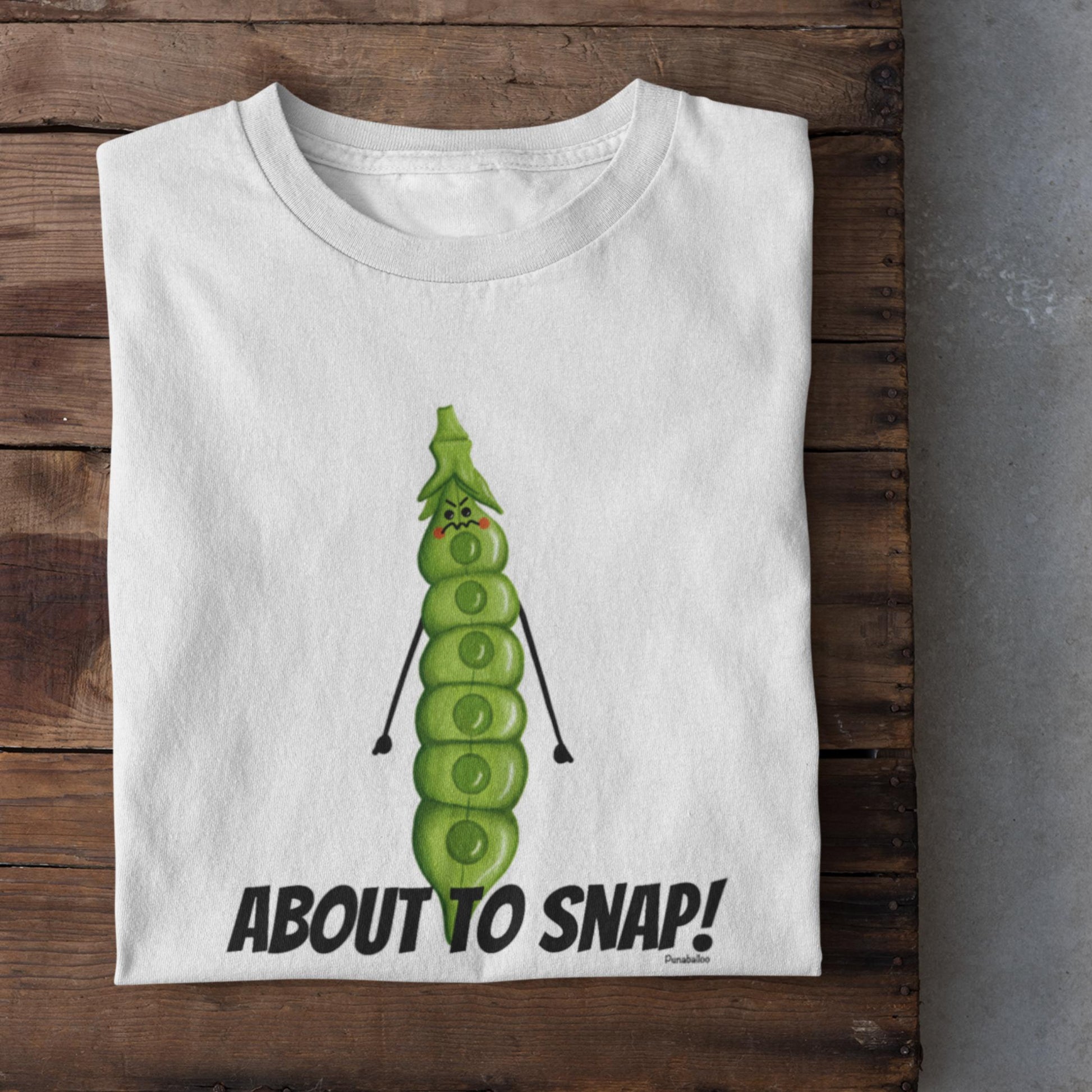 Folded white I’m About to Snap pea pun t-shirt on rustic wood background