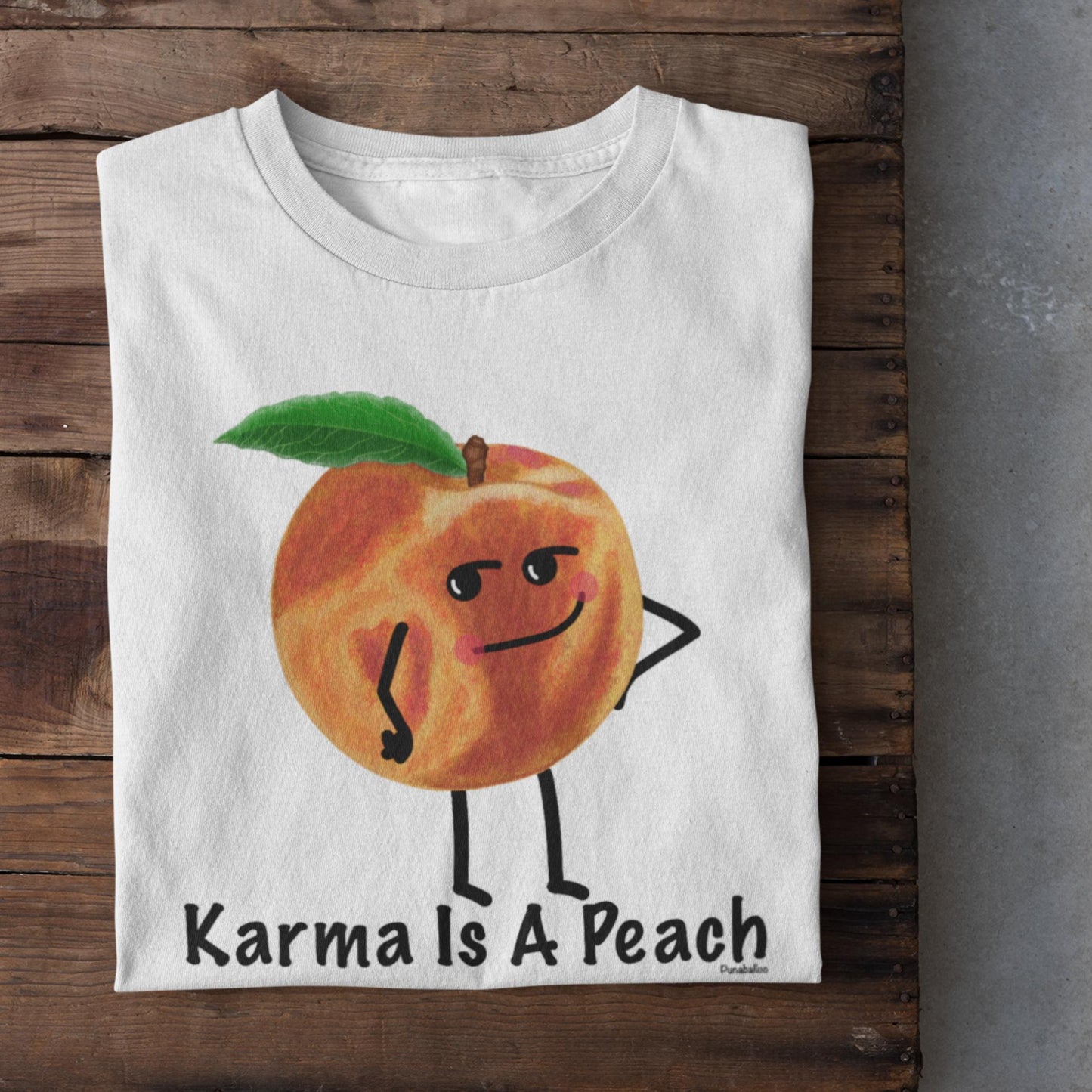 Folded white Karma Is a Peach peach t-shirt on rustic wood background