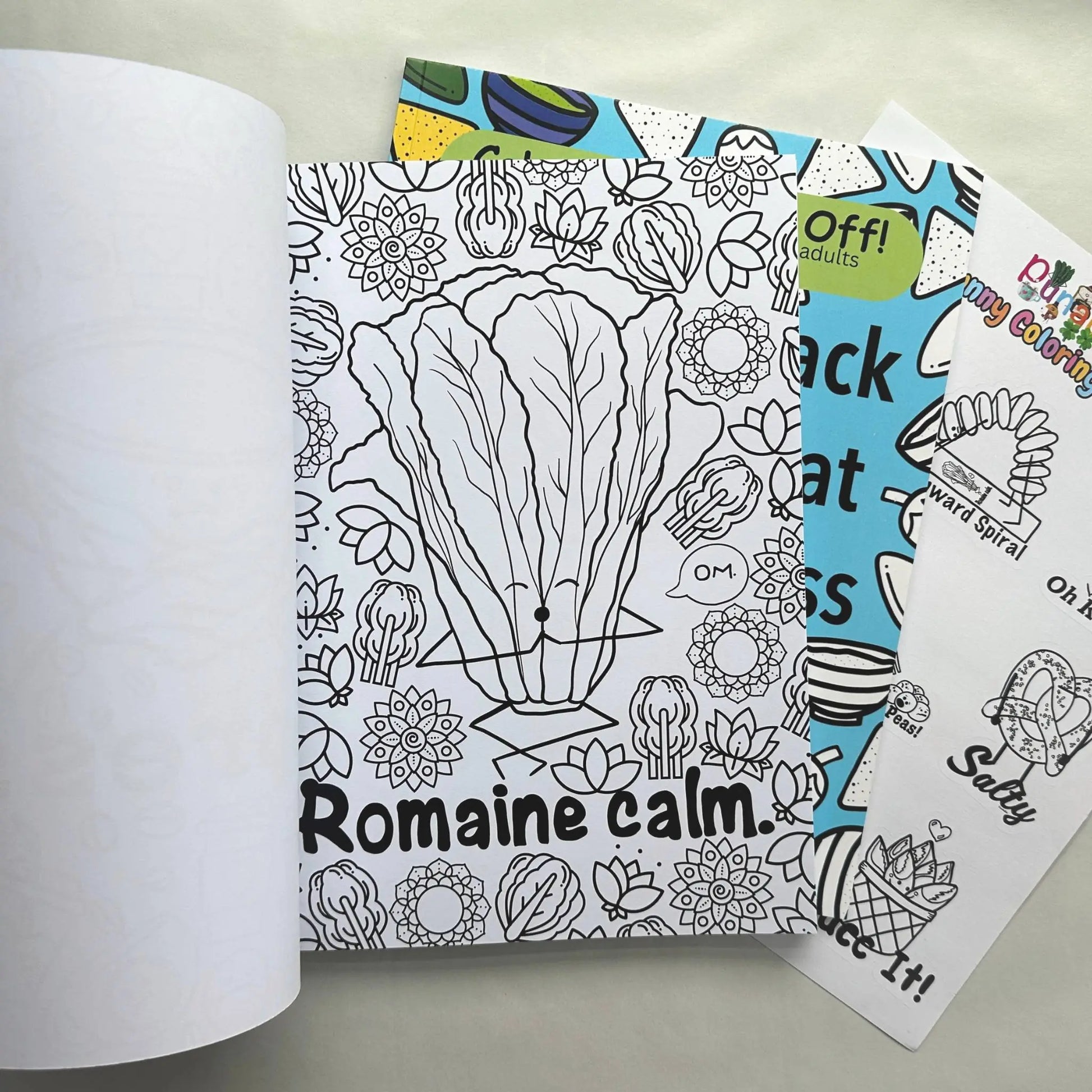 Funny food pun adult coloring book bundle open to Romaine Calm page with sticker sheet visible