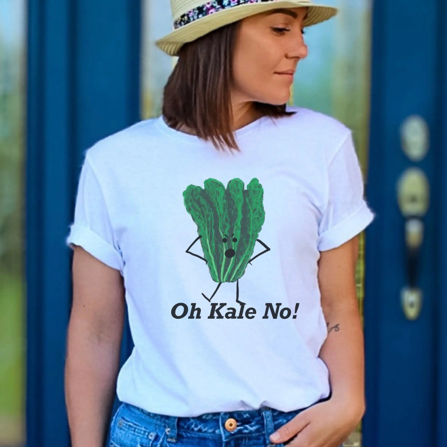 Person wearing a white t-shirt with a green kale graphic and text 'Oh Kale No!' against a blue door background.
