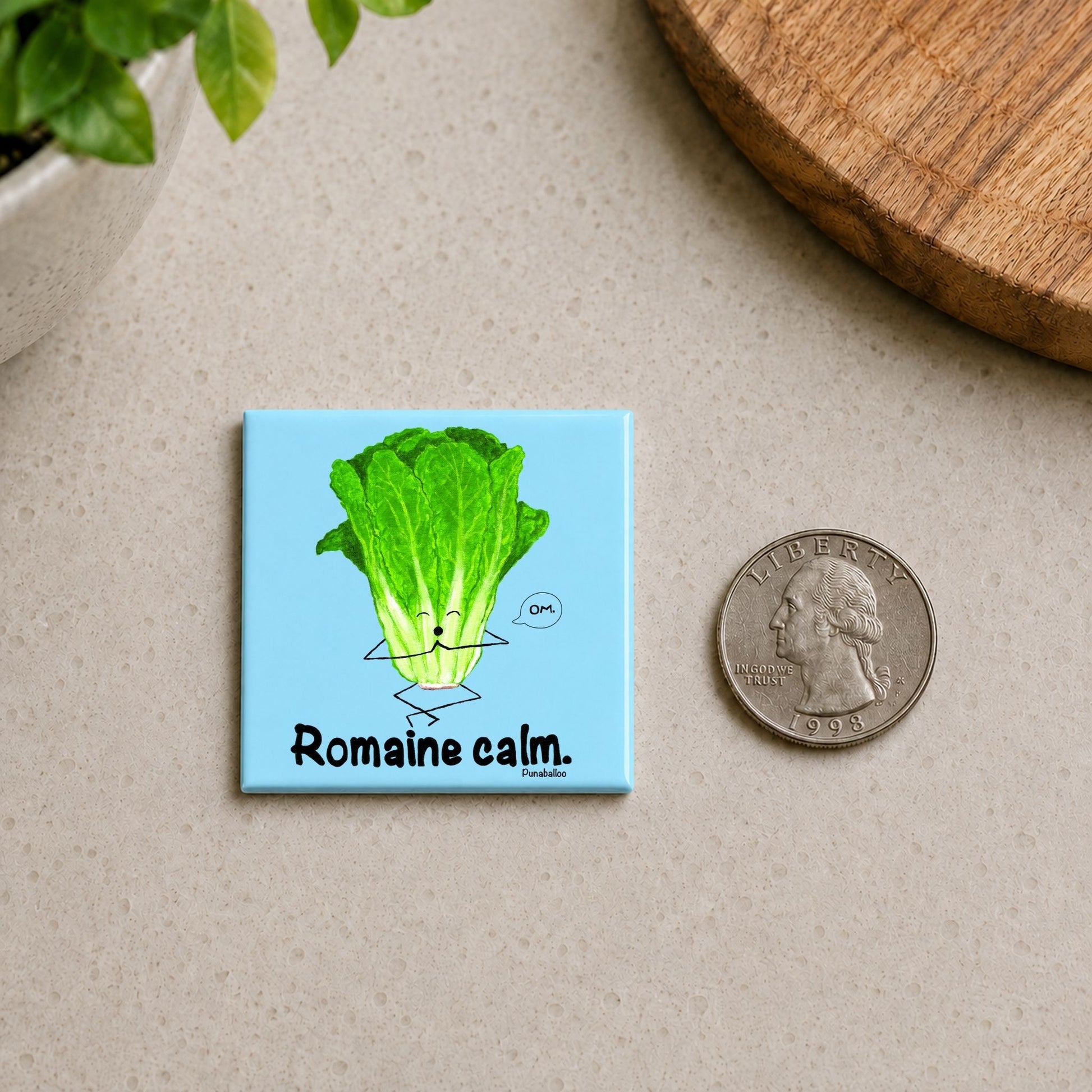 Romaine Calm magnet on a countertop beside a quarter for size