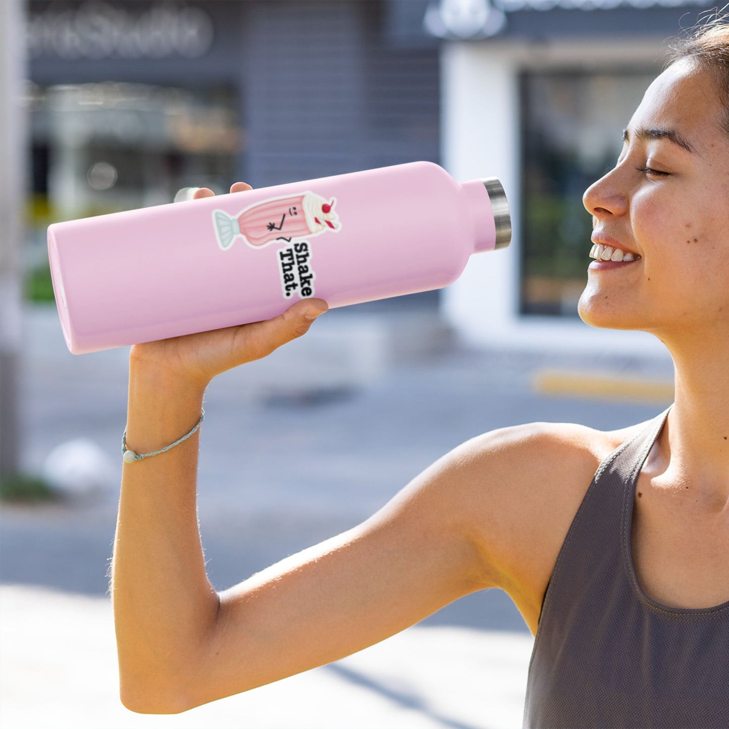 Woman drinking from a pink water bottle with Shake That sticker