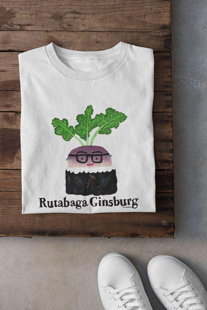 White t-shirt with a graphic design of a rutabaga wearing glasses and text 'Rutabaga Ginsburg' on a wooden surface.