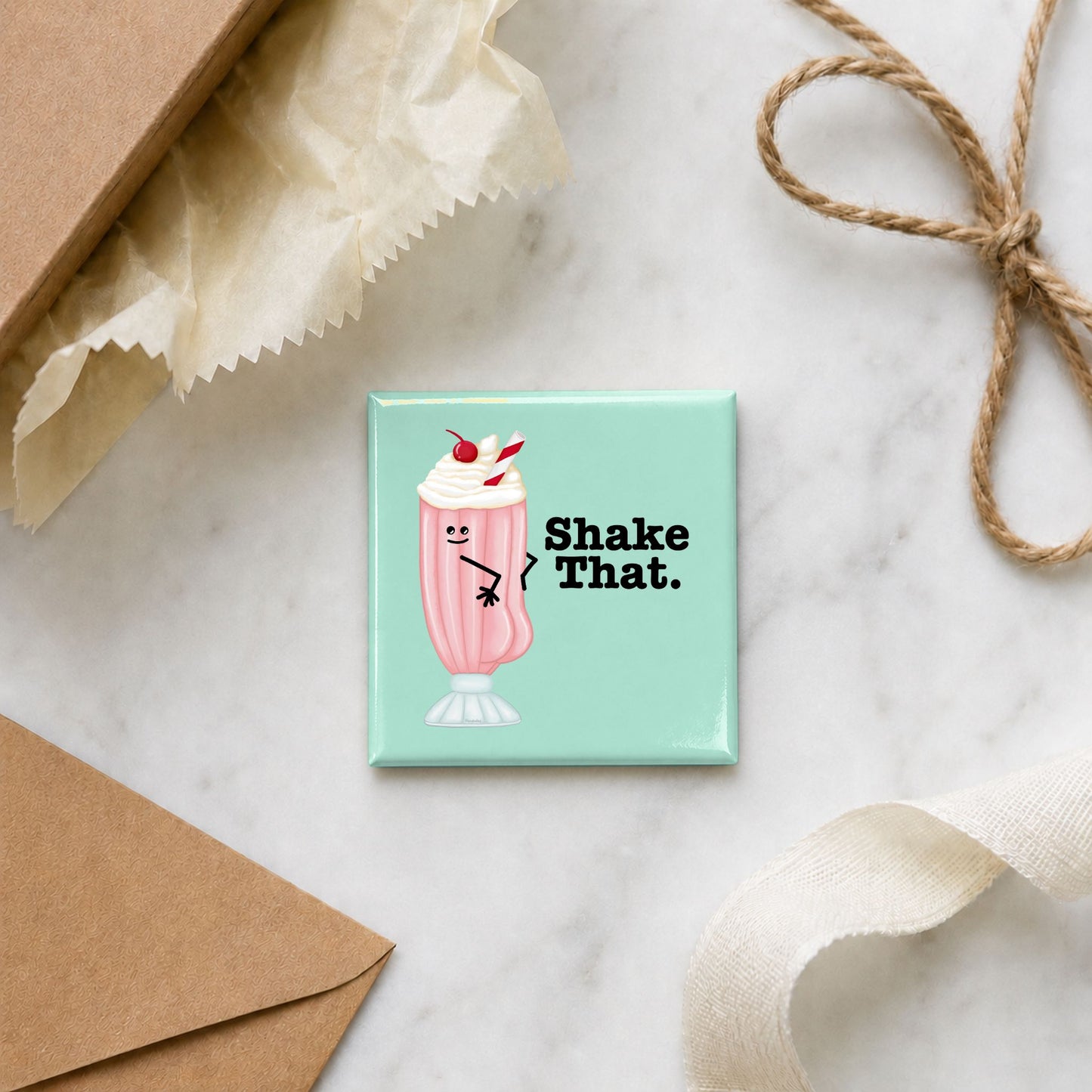 Funny ice cream magnet arranged with gift wrap, an envelope, ribbon, and twine