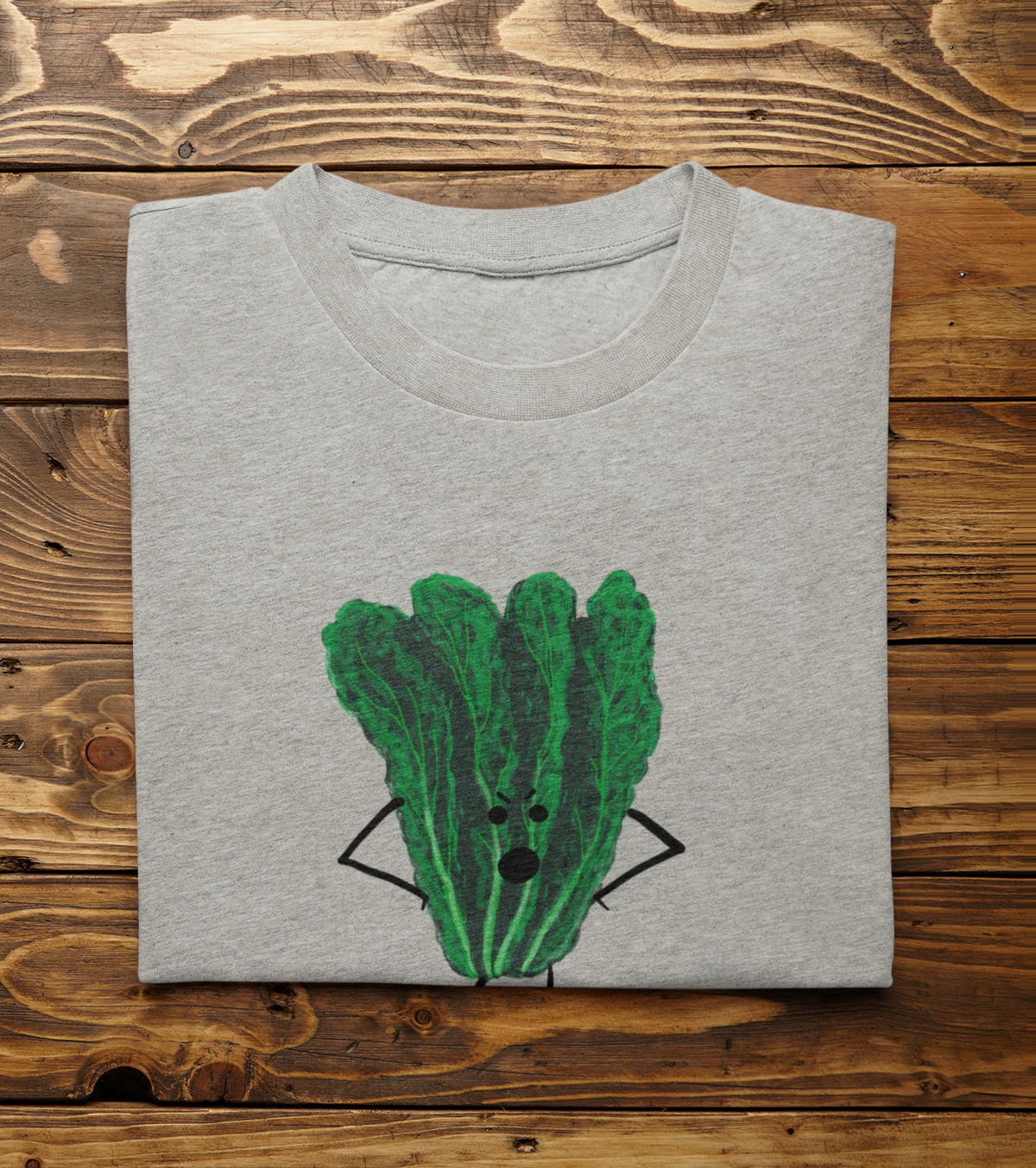 A folded light heather gray t-shirt with Oh Kale No pun printed on the front, displayed flat on a rustic wooden plank background.