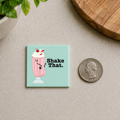 Shake That milkshake pun magnet shown beside a quarter for scale