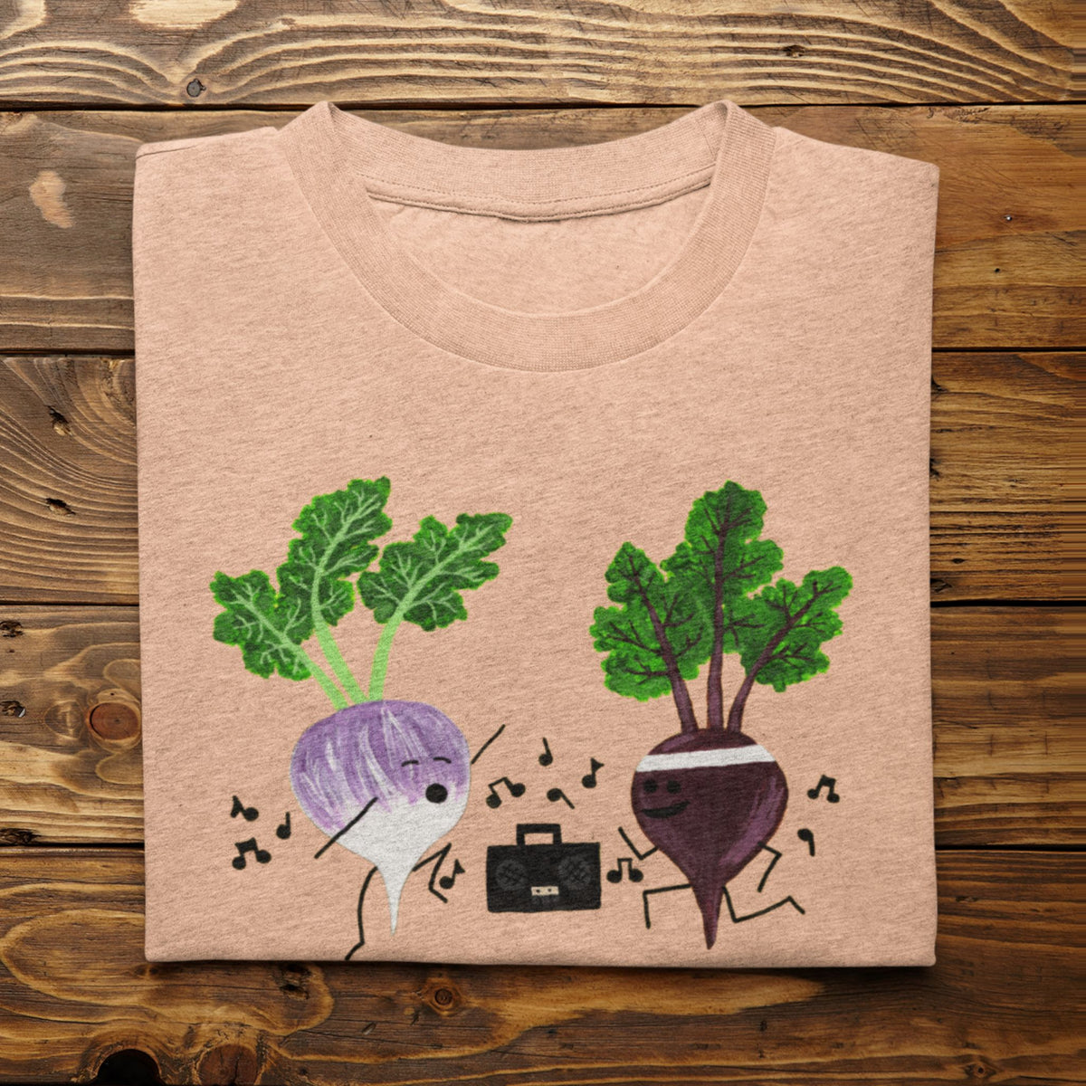 Heather Peach Turnip the Beet vegetable pun T-shirt folded on a rustic wood background