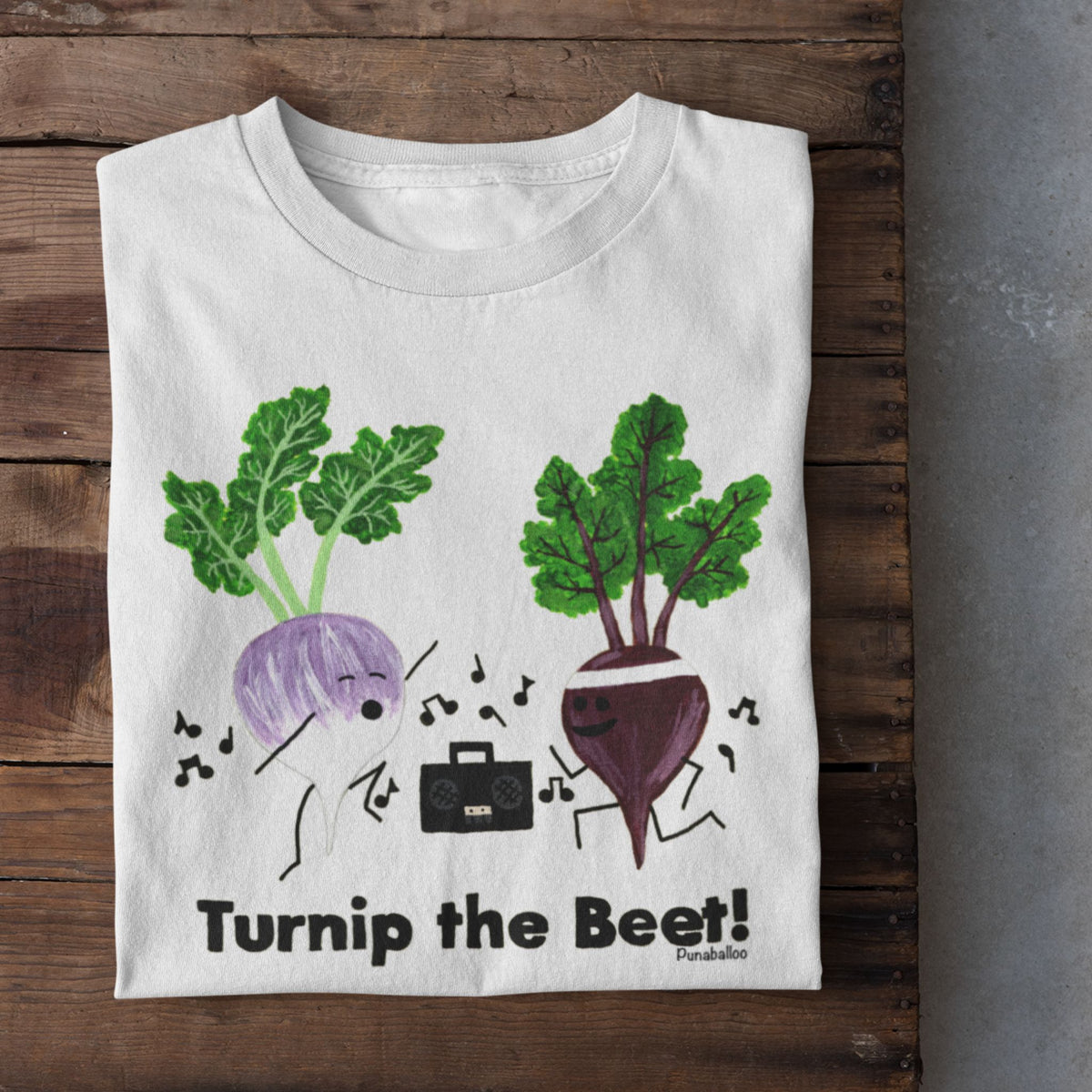 White Turnip the Beet vegetable pun T-shirt folded on a rustic wood background