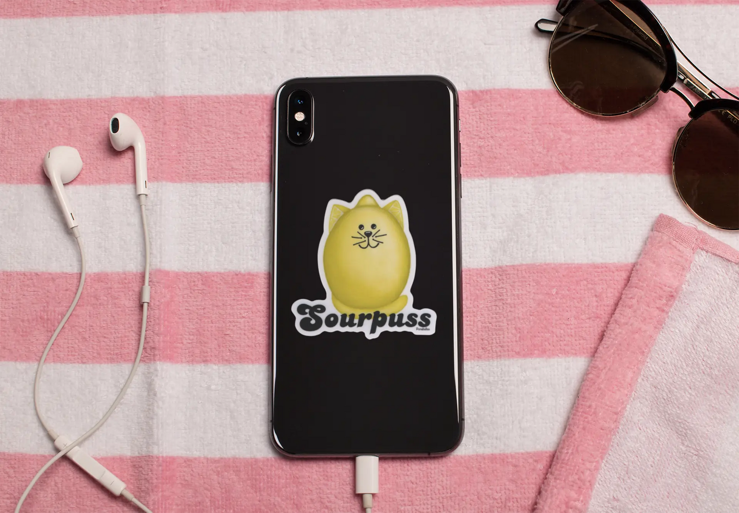 Sourpuss pun sticker featuring a lemon cat design on the back of a black phone.