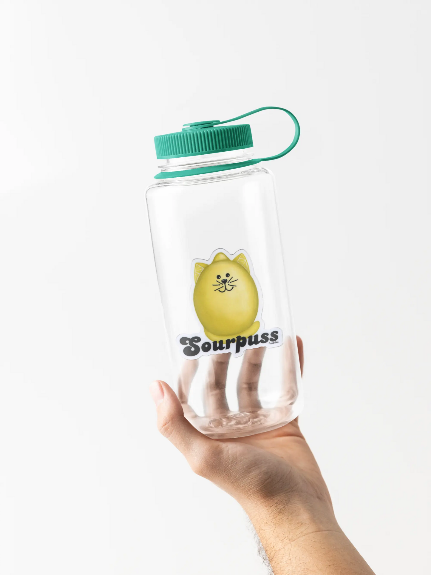 Clear water bottle with green lid and 'Sourpuss' pun sticker held by a hand on a white background