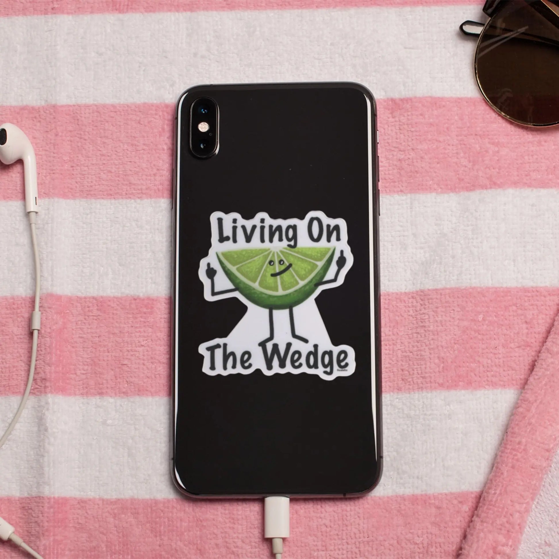 Phone case with 'Living On The Wedge' pun sticker on a pink and white striped towel 